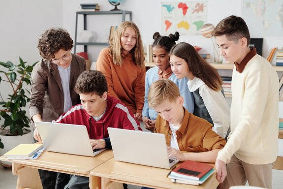 Schülerinnen und Schüler aus verschiedenen Ländern arbeiten gemeinsam am Laptop.